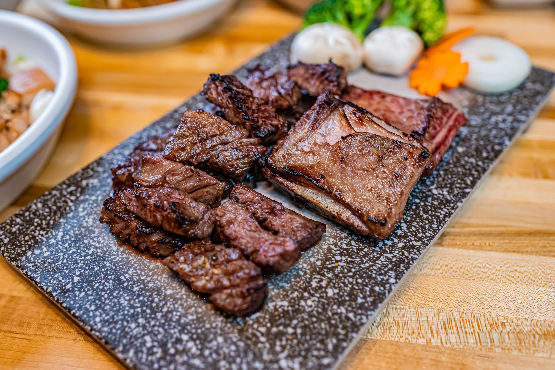 Deliciously grilled beef with vegetables on a stone plate, ready to serve.